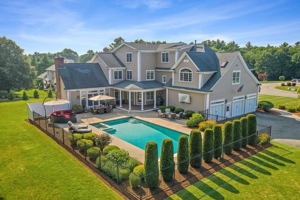 An aerial view of a large house with a large swimming pool in the backyard.