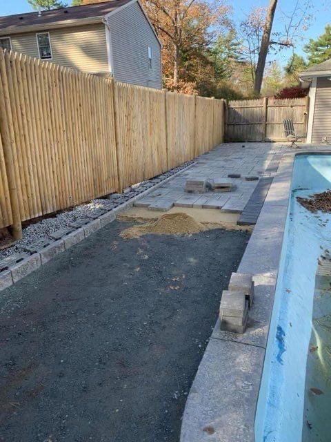 A wooden fence surrounds a swimming pool in a backyard