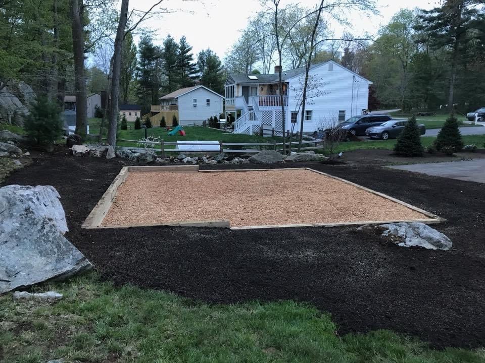 A large rock in the middle of a yard with a house in the background.