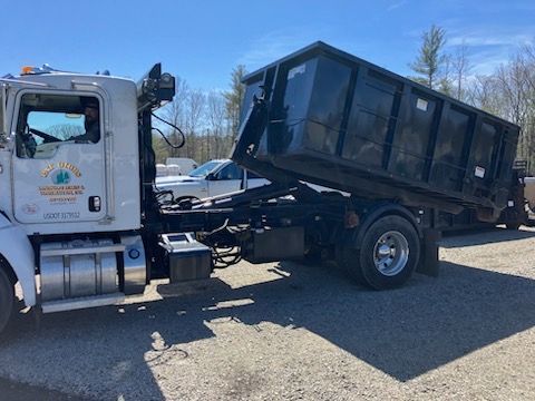 A dump truck is parked in a gravel lot.
