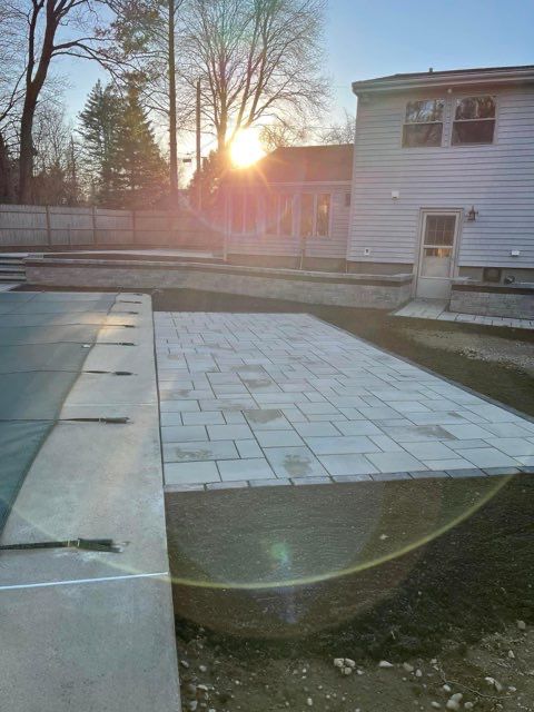 The sun is setting behind a house in the background