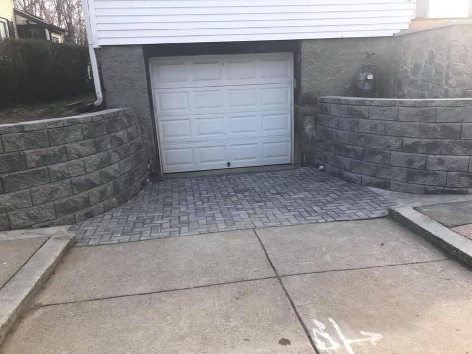 A white garage door is sitting next to a brick wall.
