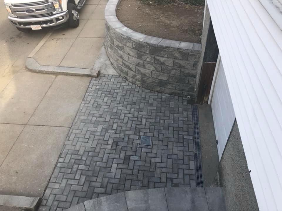 A truck is parked on the side of the road next to a brick walkway
