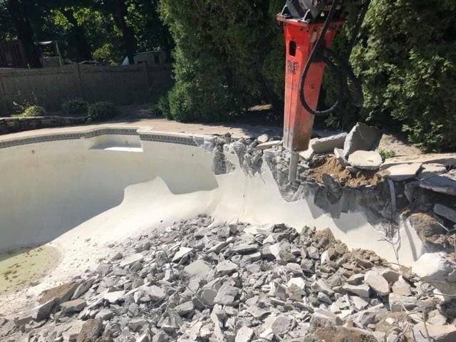 A large pile of rocks is being removed from a swimming pool.