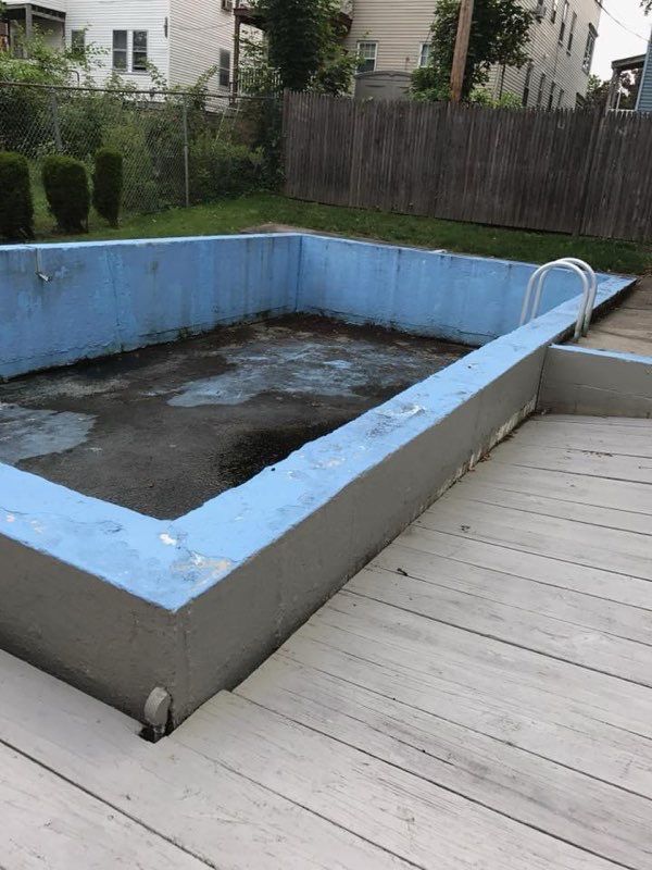 A blue swimming pool is sitting on top of a wooden deck.