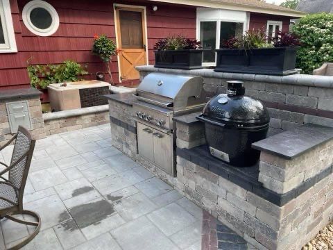 A patio with a grill and a pot on it in front of a red house.