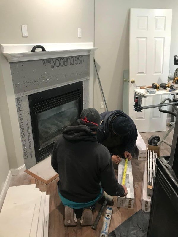 A group of men are working on a fireplace in a living room.