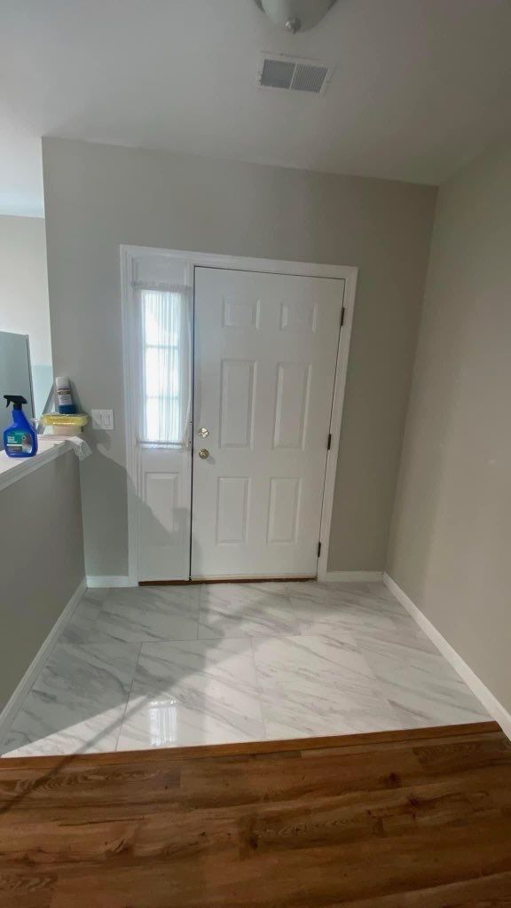 A hallway with a white door and a wooden floor in a house.