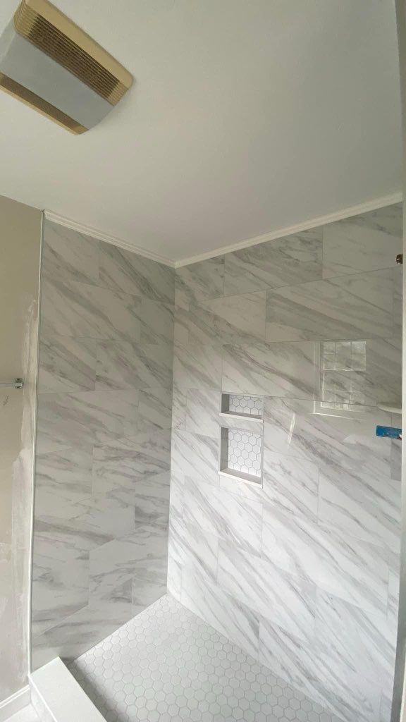 A bathroom with marble tile walls and a walk in shower.