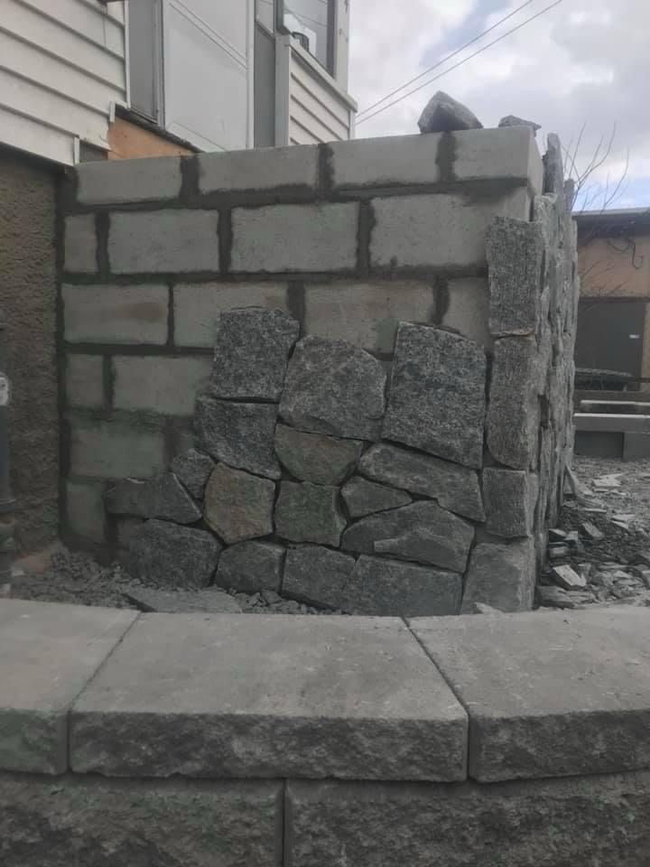 A stone wall is being built in front of a house.