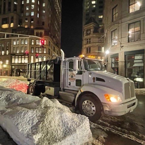 A white truck is parked on a snowy street at night