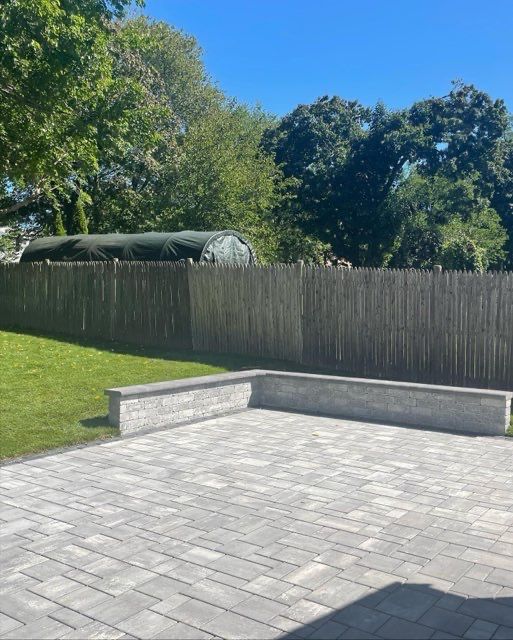 A brick patio with a wooden fence in the background.