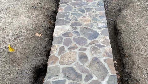 A stone walkway is being built in the dirt.