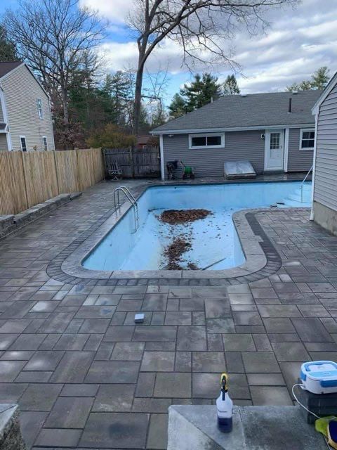 A large swimming pool is sitting in the backyard of a house.