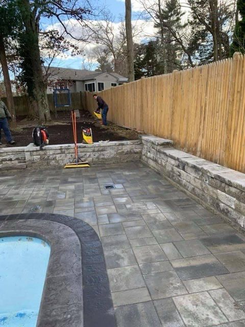 A man is working on a patio next to a pool.