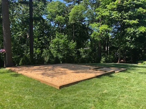 A large wooden platform is sitting in the middle of a lush green field.