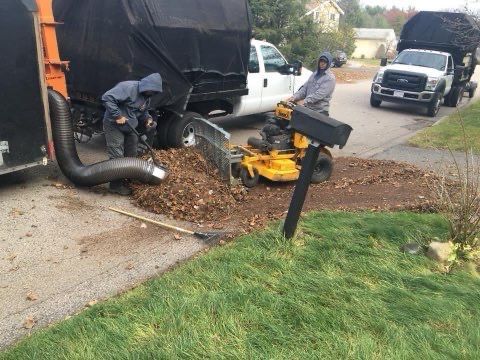 A man is riding a lawn mower next to a mailbox.