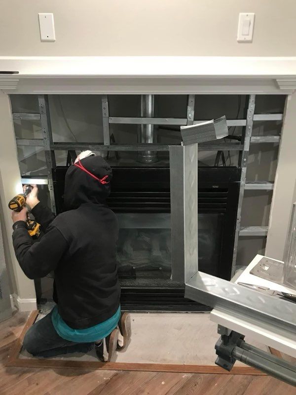 A man is installing a fireplace in a living room.