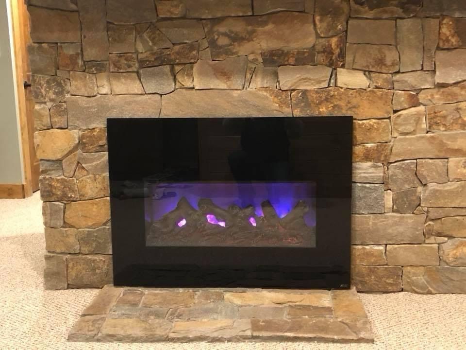 A fireplace with a stone wall and a purple light on it.