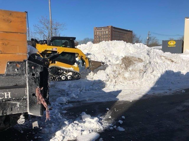 A large pile of snow is being cleared by a bulldozer