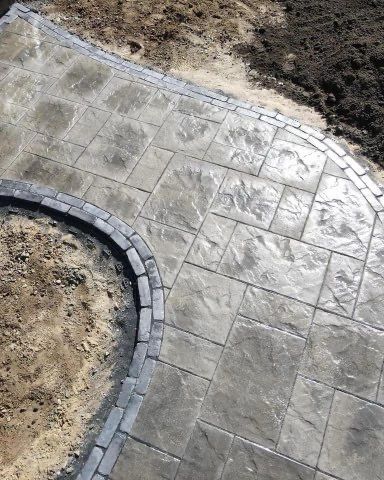 A close up of a concrete walkway with a brick border.