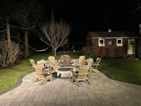 A patio with a fire pit and chairs at night.