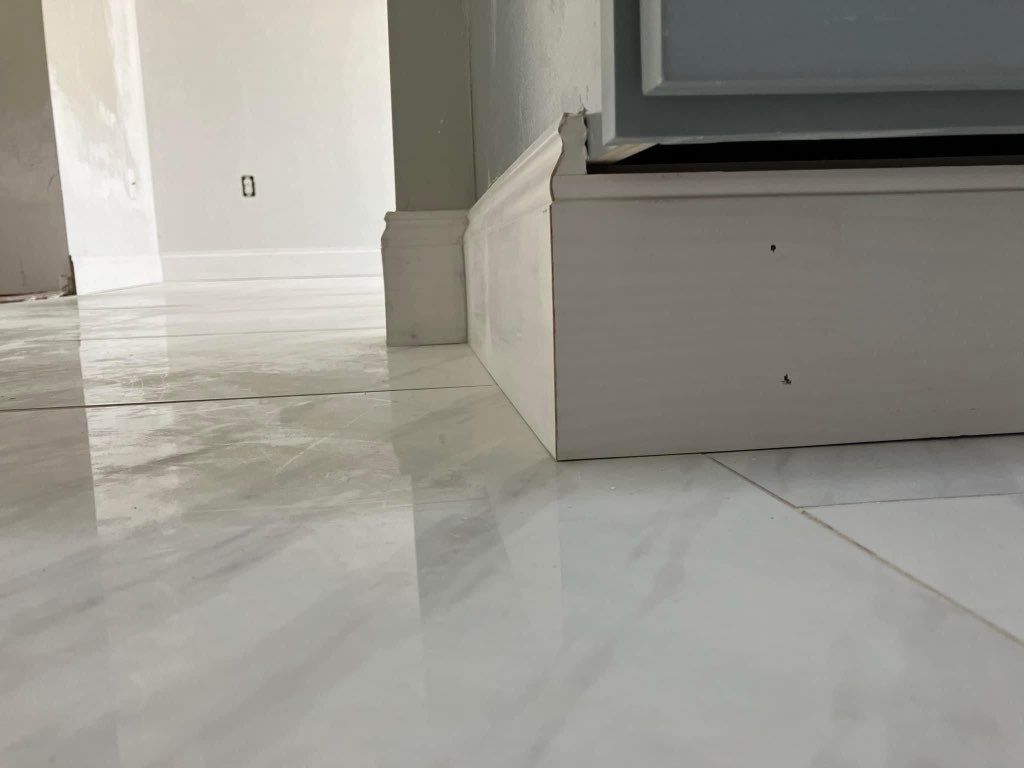 A close up of a white tile floor in a room.