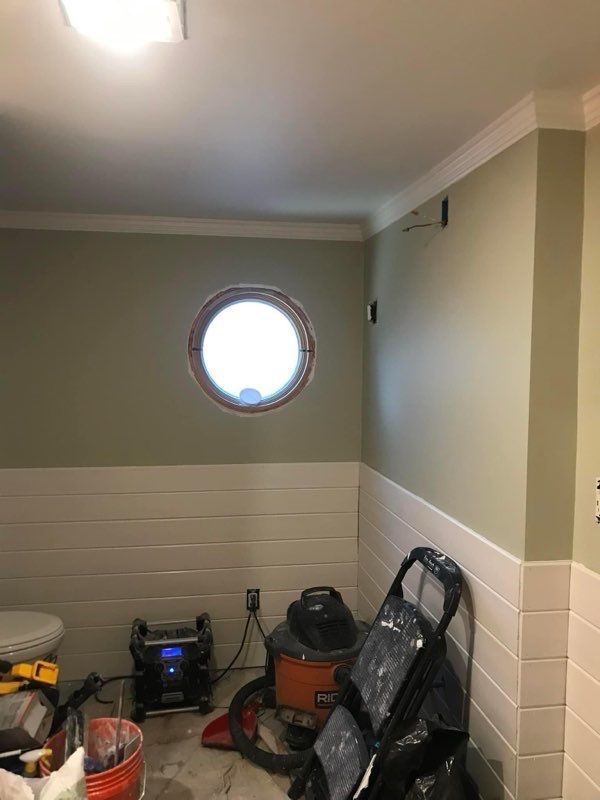A bathroom with a round window and a vacuum cleaner.