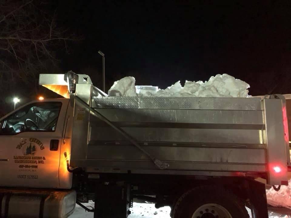A dump truck is filled with snow at night.