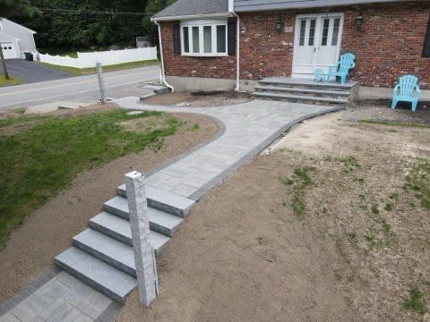 A brick house with a walkway and stairs in front of it.