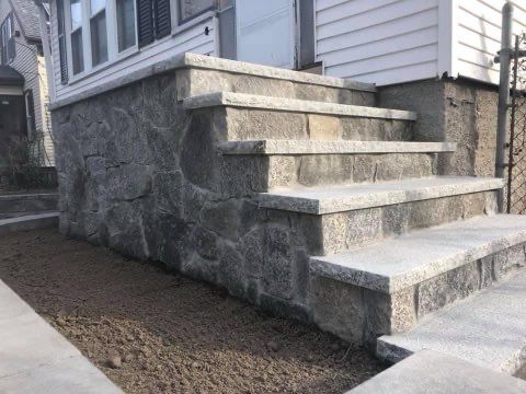 A stone wall with stairs leading up to a house.