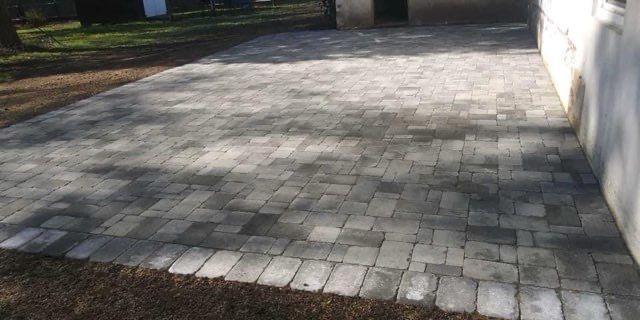 A brick driveway is being built in front of a house.
