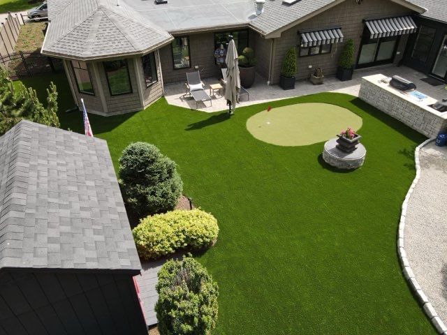 An aerial view of a house with a lush green lawn and a putting green.