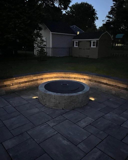 A fire pit is lit up at night on a patio