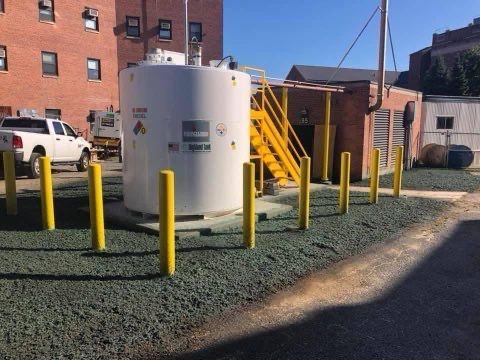 A white truck is parked in front of a large white tank