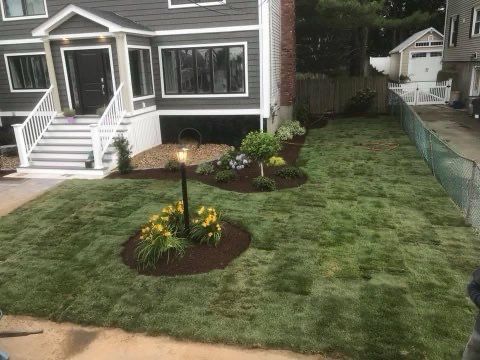 A house with a lush green lawn and flowers in front of it.