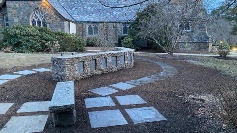 A stone bench is sitting in front of a stone building.