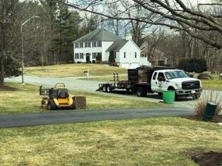 A truck and a lawn mower are parked in front of a house.