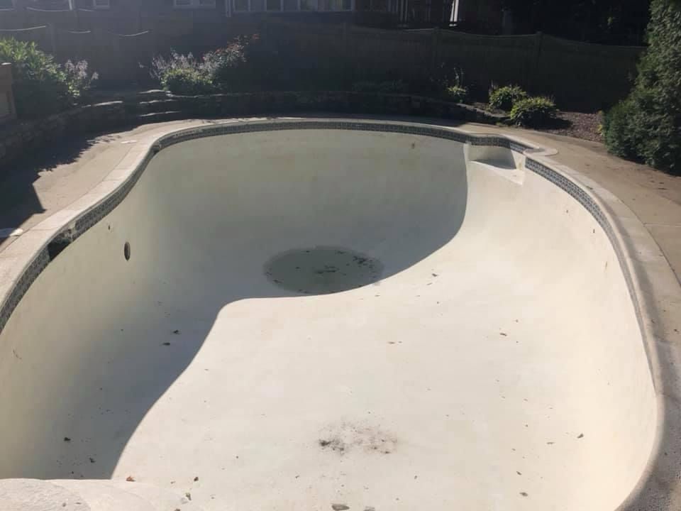 An empty swimming pool is sitting on top of a concrete surface.