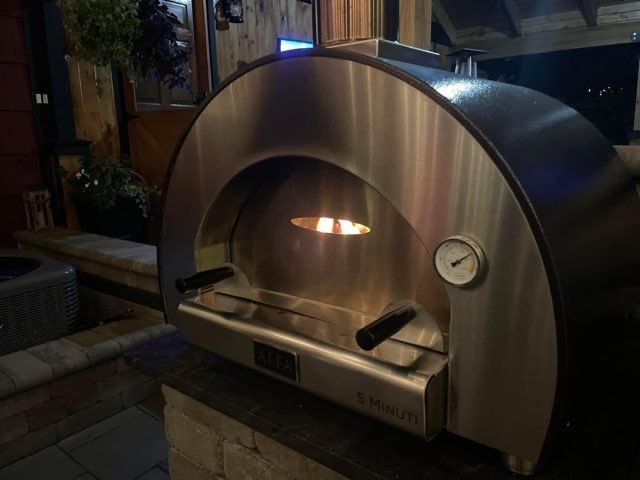 A stainless steel pizza oven with a clock on it