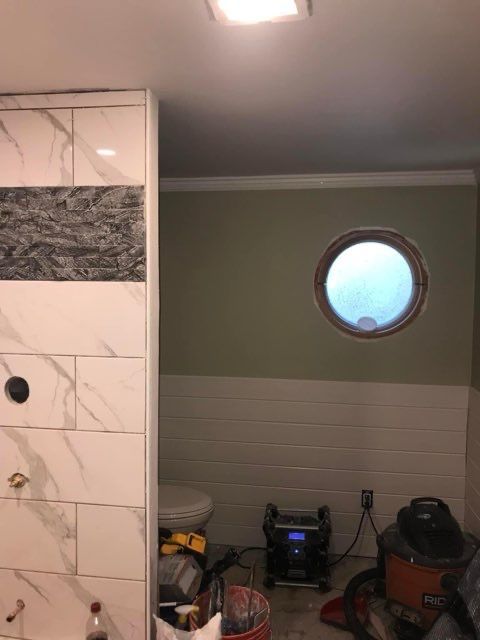 A bathroom with white tiles and a round window.