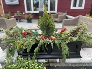 A black planter filled with christmas decorations is sitting on a patio.