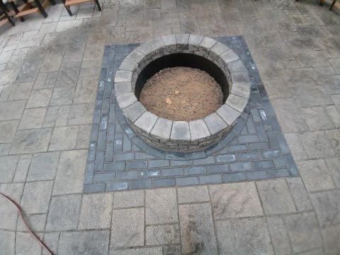 A fire pit is surrounded by bricks on a patio.
