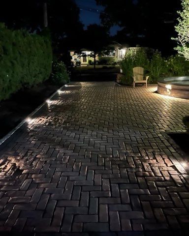 A brick walkway with lights on it at night.