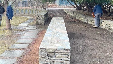 A stone wall is being built next to a stone walkway.