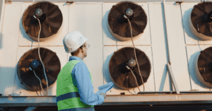 Engineer in safety vest and hard hat inspects HVAC unit.