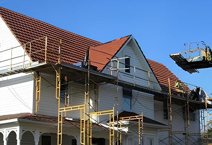 A white house with a red tile roof is under construction