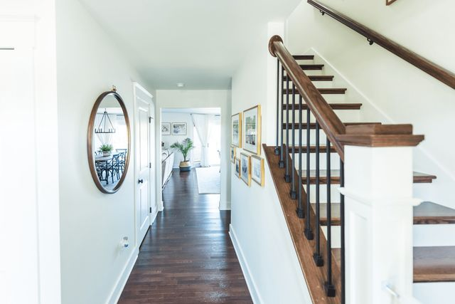 A hallway with stairs and a mirror on the wall.