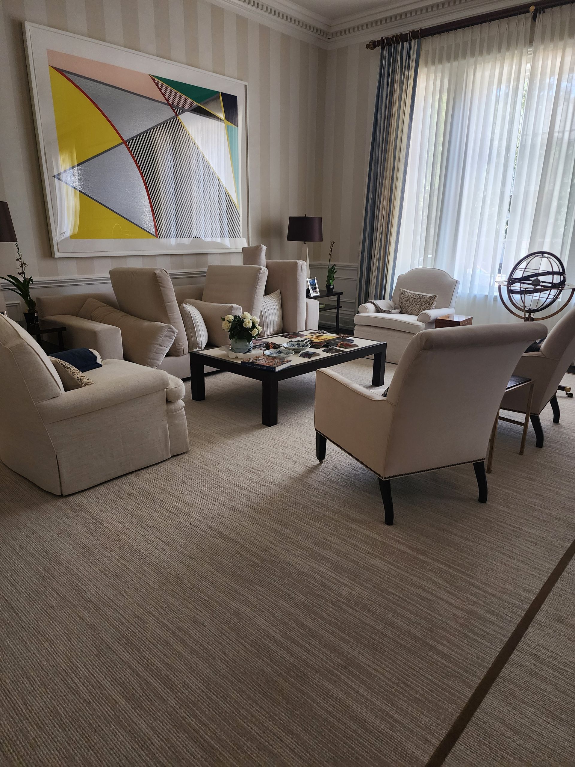 Living room with beige furniture, a large colorful painting, and a dark wood coffee table.