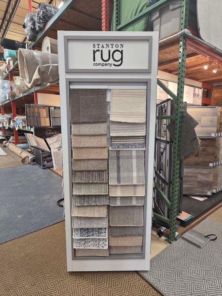 Carpet display stand in a warehouse with various rug samples.